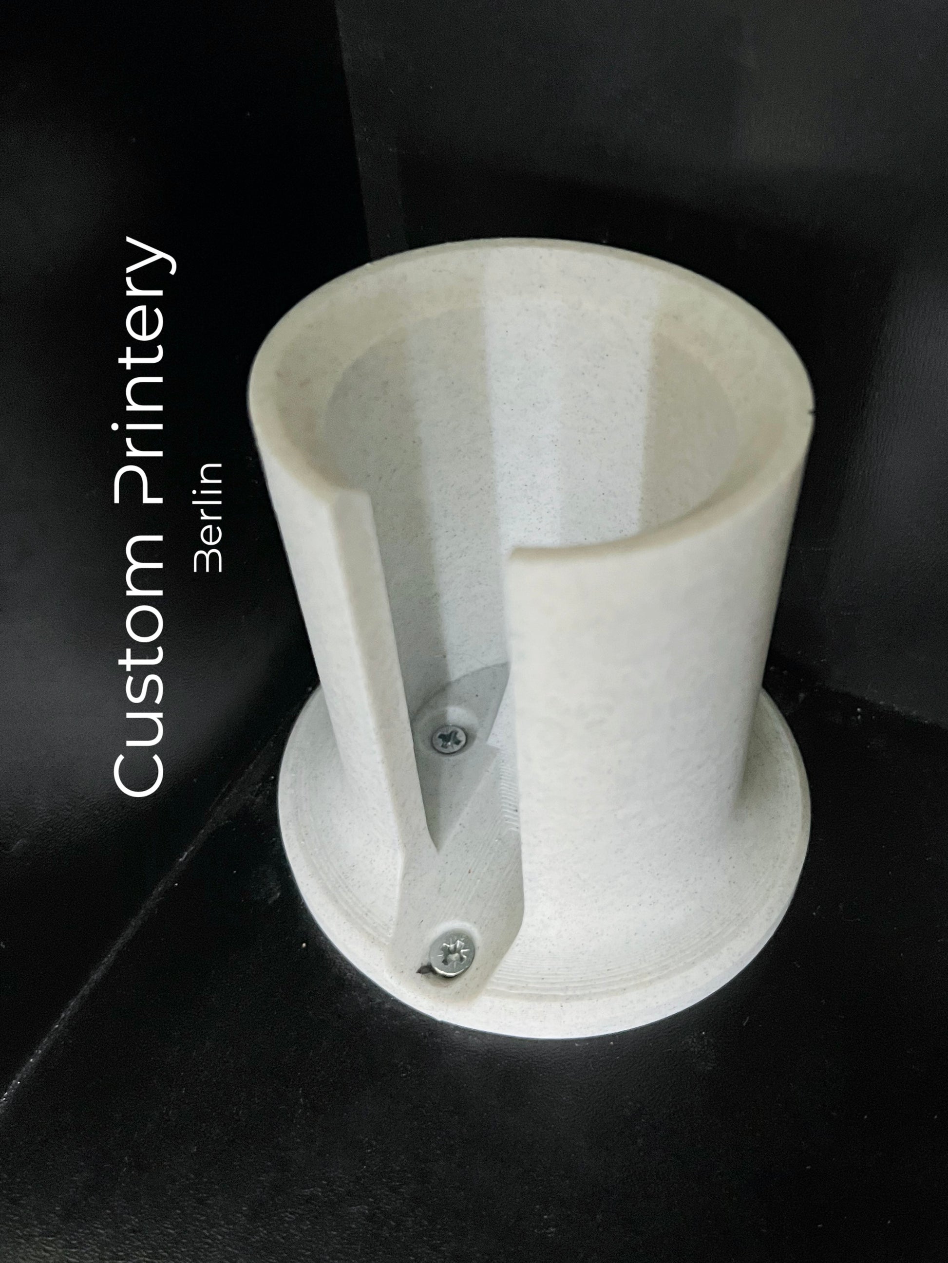 Schwarze Wandhalterung für Dyson Haarstyling-Gerät und Zubehör. Die Halterung enthält den Haartrockner, verschiedene Styling-Aufsätze und ist sauber organisiert. Oben auf dem Regal steht eine moderne Vase mit getrockneten Eukalyptuszweigen.