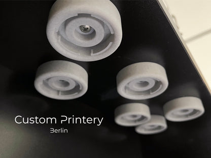 Schwarze Wandhalterung für Dyson Haarstyling-Gerät und Zubehör. Die Halterung enthält den Haartrockner, verschiedene Styling-Aufsätze und ist sauber organisiert. Oben auf dem Regal steht eine moderne Vase mit getrockneten Eukalyptuszweigen.