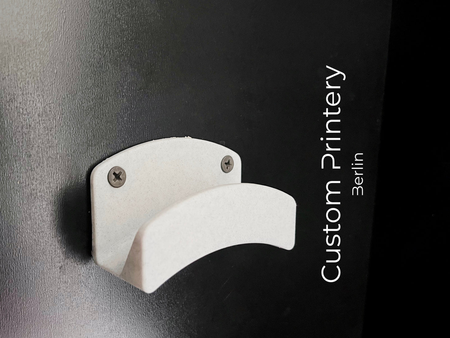 Schwarze Wandhalterung für Dyson Haarstyling-Gerät und Zubehör. Die Halterung enthält den Haartrockner, verschiedene Styling-Aufsätze und ist sauber organisiert. Oben auf dem Regal steht eine moderne Vase mit getrockneten Eukalyptuszweigen.