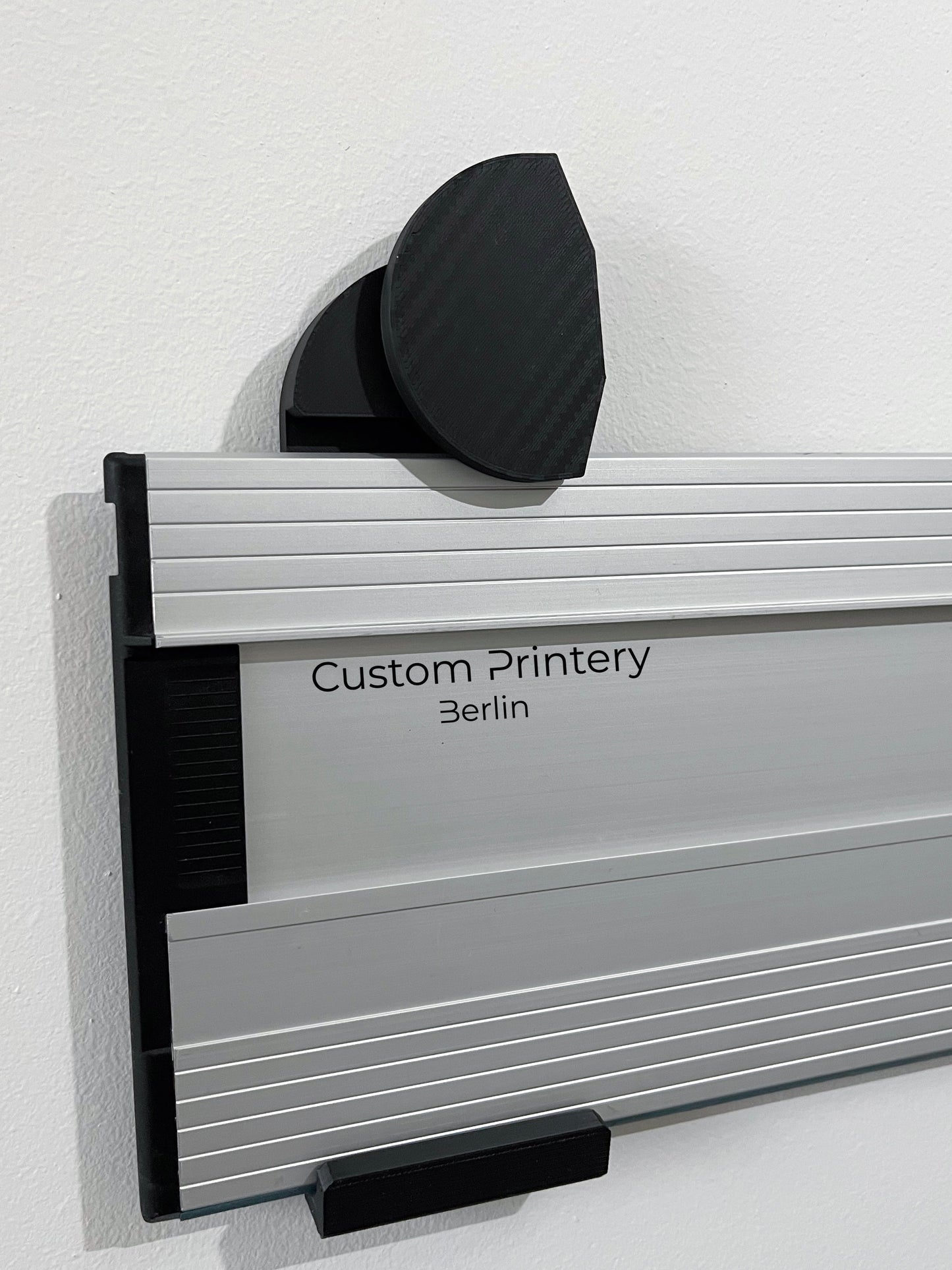 Schwarze Halterung für Bosch FSN Führungsschienen, montierbar an Wand oder Decke. Ideal zur sicheren, platzsparenden Aufbewahrung in Werkstätten. Arretiermechanismus für stabilen Halt, einfache Befestigung durch Schrauben oder Klebeband