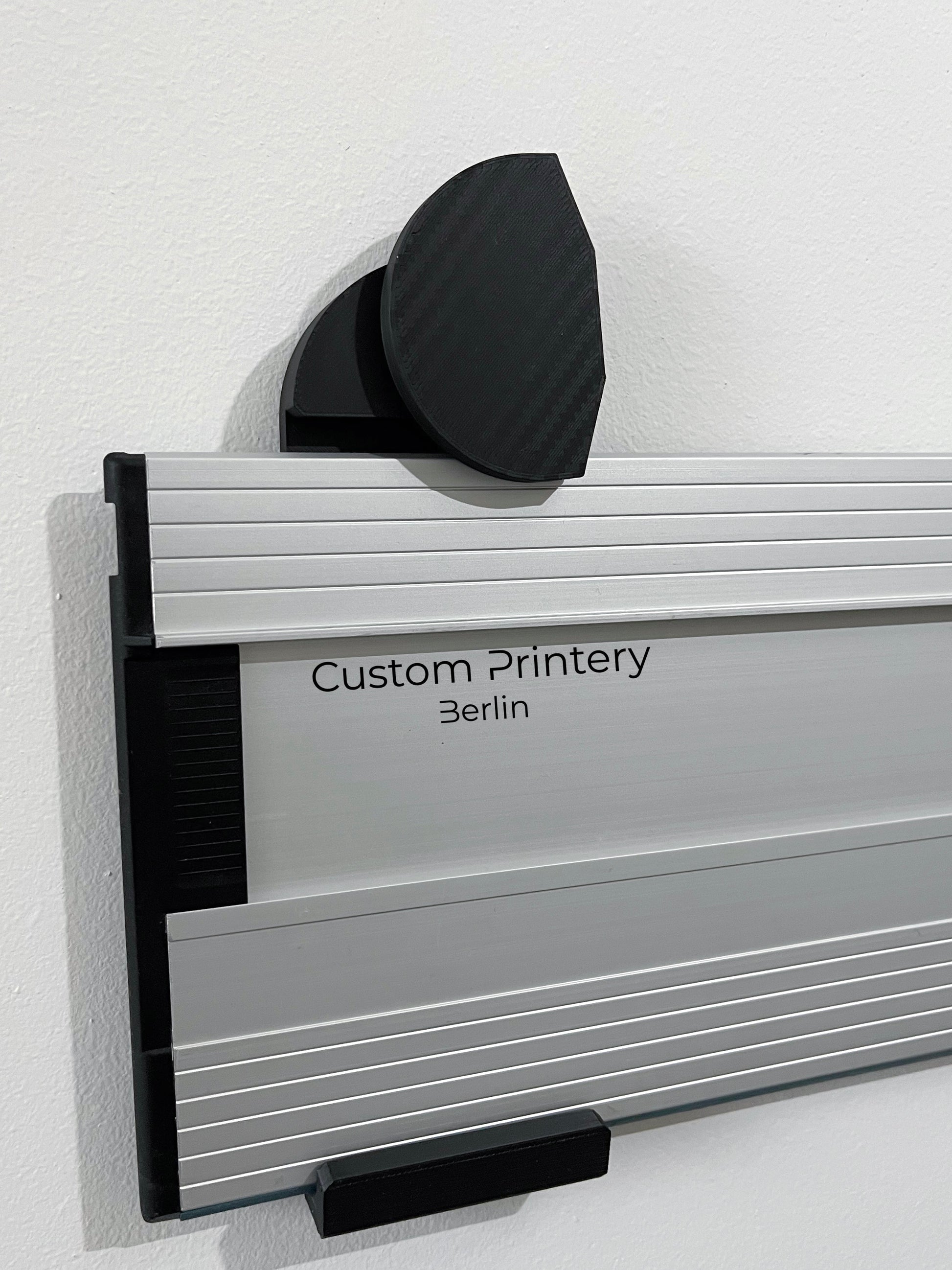 Schwarze Halterung für Bosch FSN Führungsschienen, montierbar an Wand oder Decke. Ideal zur sicheren, platzsparenden Aufbewahrung in Werkstätten. Arretiermechanismus für stabilen Halt, einfache Befestigung durch Schrauben oder Klebeband