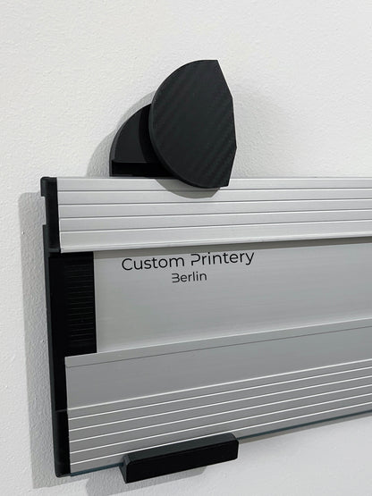 Schwarze Halterung für Bosch FSN Führungsschienen, montierbar an Wand oder Decke. Ideal zur sicheren, platzsparenden Aufbewahrung in Werkstätten. Arretiermechanismus für stabilen Halt, einfache Befestigung durch Schrauben oder Klebeband