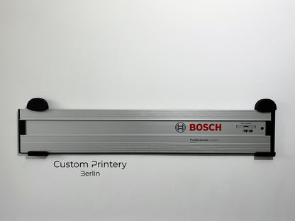 Schwarze Halterung für Bosch FSN Führungsschienen, montierbar an Wand oder Decke. Ideal zur sicheren, platzsparenden Aufbewahrung in Werkstätten. Arretiermechanismus für stabilen Halt, einfache Befestigung durch Schrauben oder Klebeband
