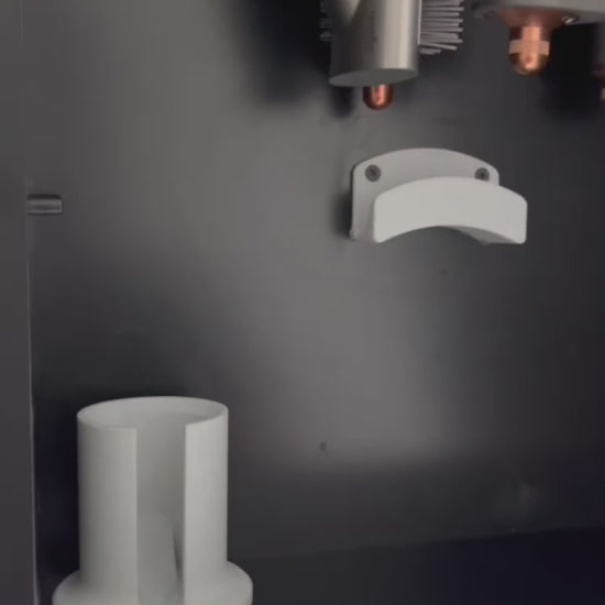 Schwarze Wandhalterung für Dyson Haarstyling-Gerät und Zubehör. Die Halterung enthält den Haartrockner, verschiedene Styling-Aufsätze und ist sauber organisiert. Oben auf dem Regal steht eine moderne Vase mit getrockneten Eukalyptuszweigen.